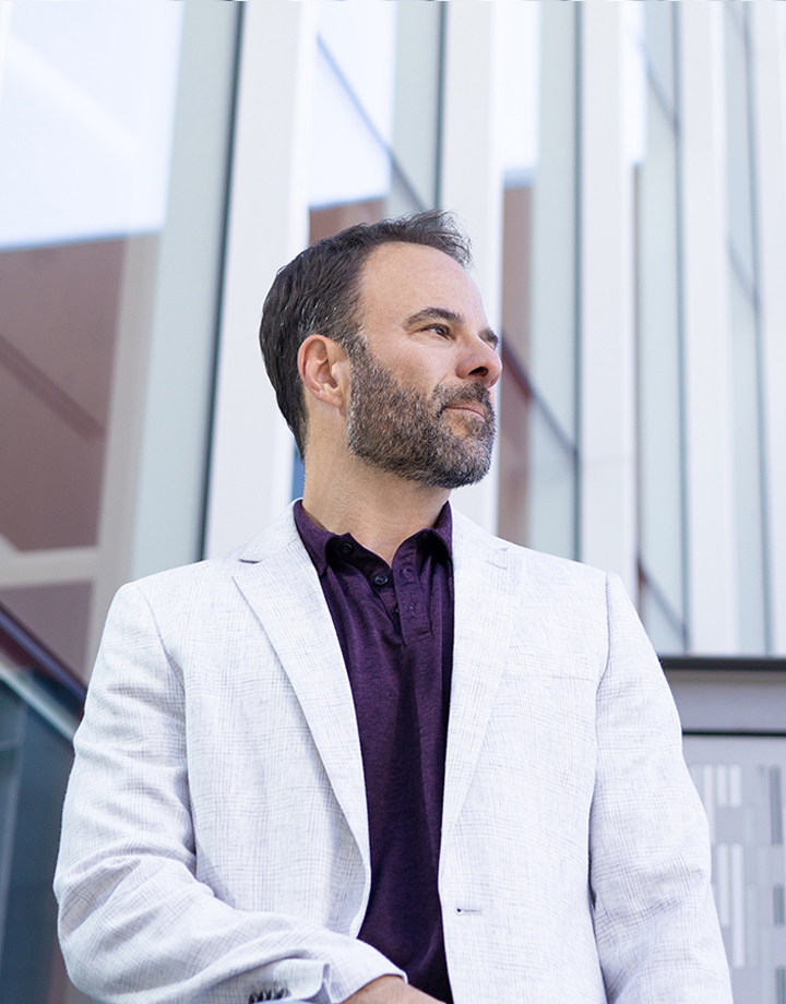 Brad Costanzo in a white blazer looking toward the headline